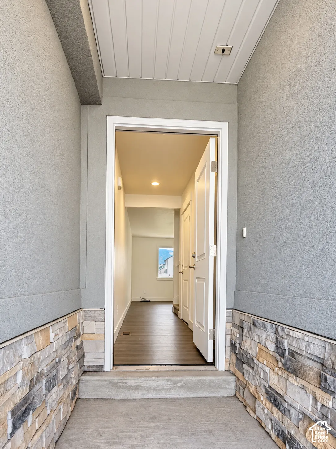 Entryway featuring a stone veneer facade, recessed ceiling lighting, and wood-finish flooring