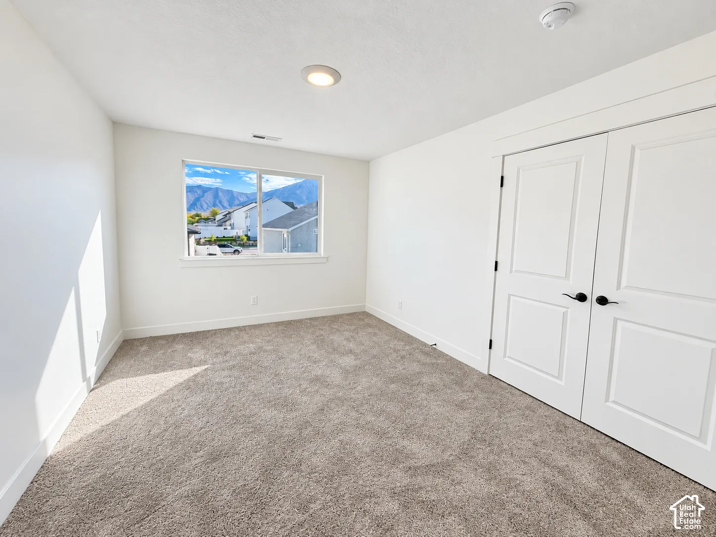 Room featuring wall-to-wall carpeting, dual-panel closet doors with matte black hardware, recessed lighting, and a window with mountain scenery