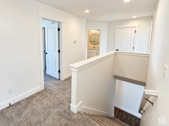 Interior landing featuring neutral-toned carpeting, recessed ceiling lighting, crisp white trim, and paneled interior doors