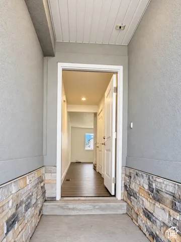Entryway featuring a stone veneer facade, recessed ceiling lighting, and wood-finish flooring