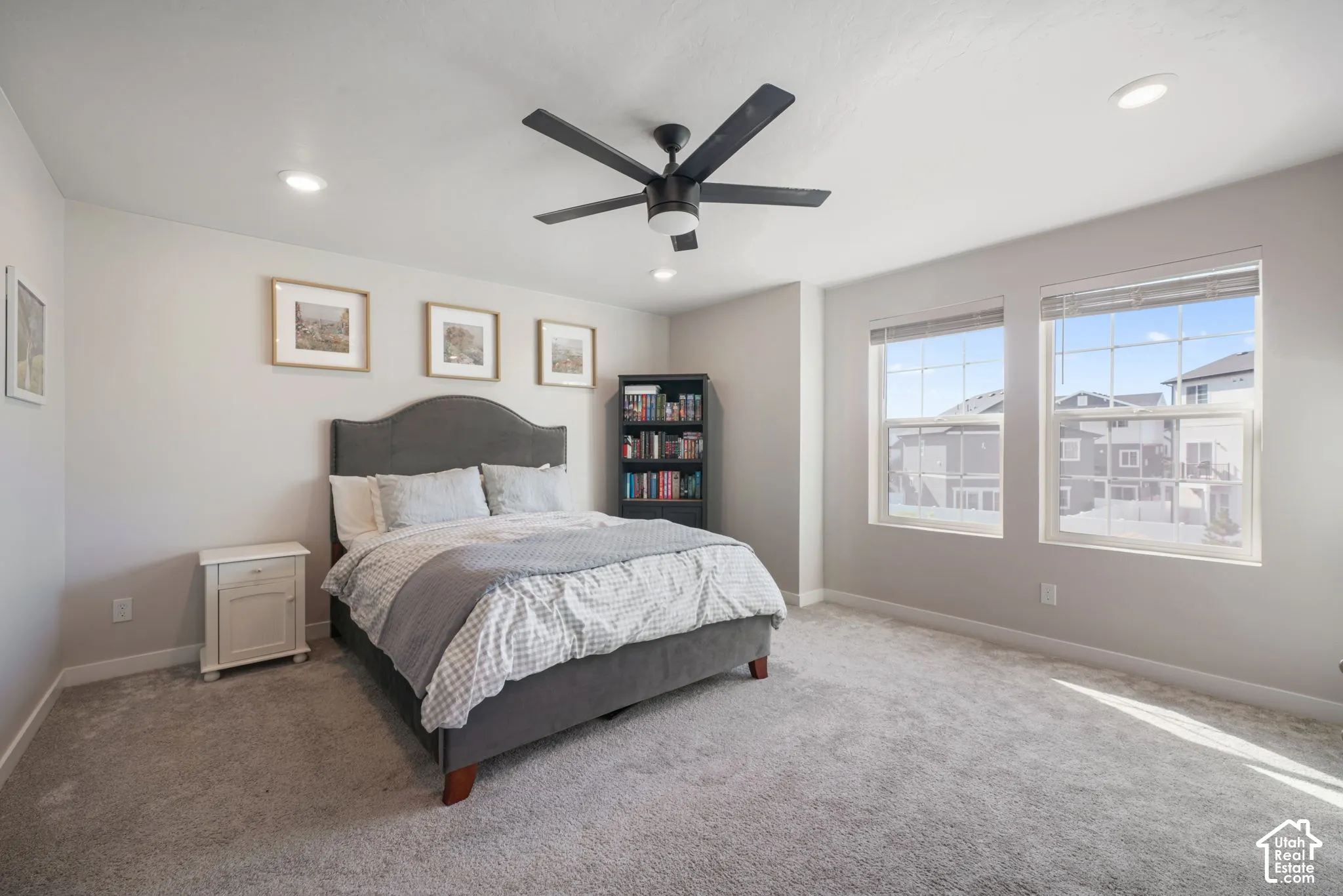 Neutral-toned room featuring carpeted flooring, two large windows with blinds, recessed lighting, and a matte black ceiling fan
