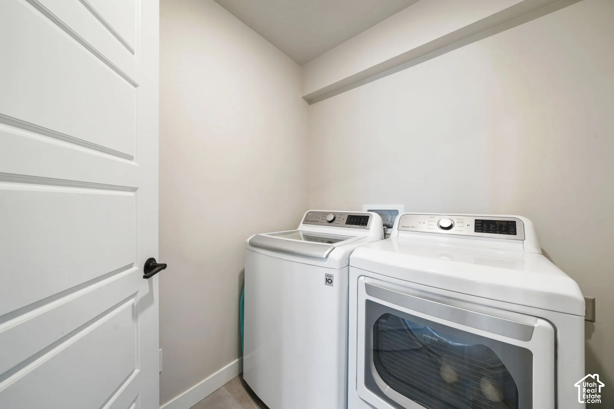Dedicated laundry area featuring a white four-panel interior door with matte black hardware