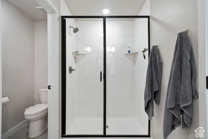 Walk-in shower featuring white subway tile surround, integrated corner shelving, and a matte black-framed glass enclosure