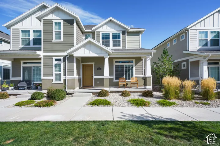 Two-story exterior featuring lap siding, white trim accents, a covered front porch with square columns, and rock landscaping