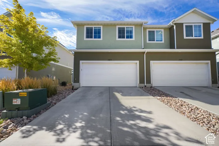 Two-story exterior featuring a dual-tone facade, concrete driveway, attached two-car garage, and low-maintenance rock landscaping