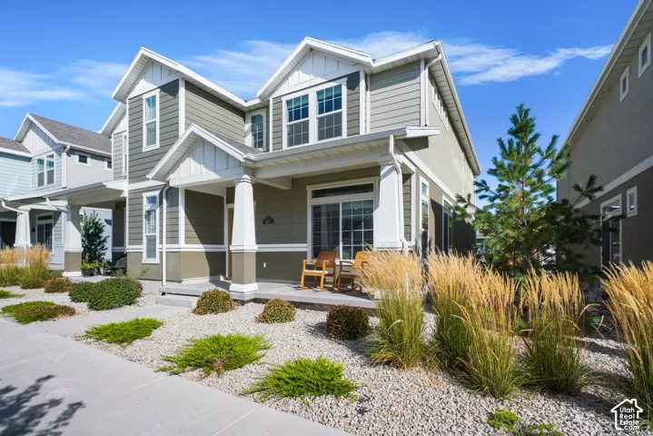 Two-story exterior with horizontal siding, covered front porch featuring decorative columns, and xeriscaped front yard with ornamental grasses