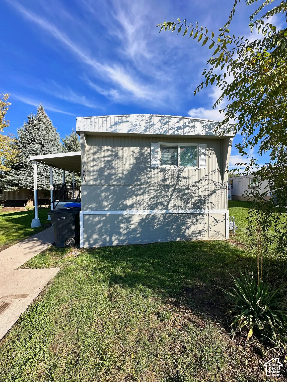 Exterior featuring light-toned horizontal siding, a covered porch, and a concrete walkway