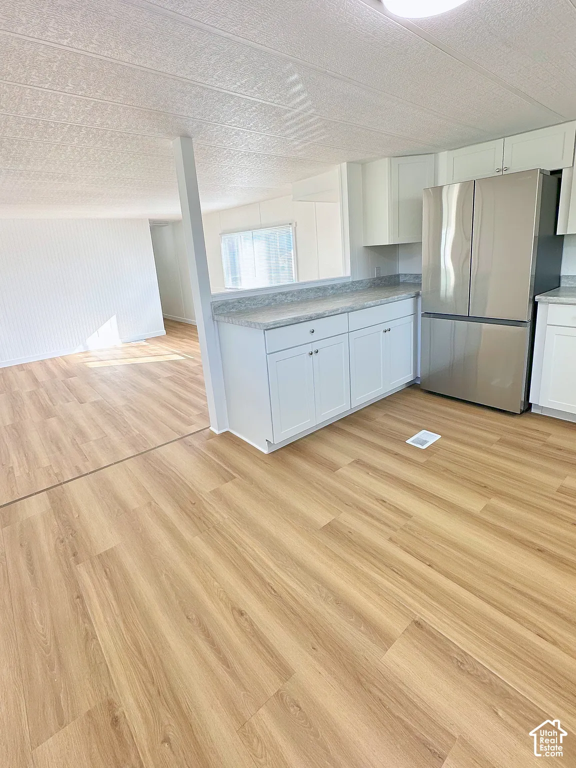 Kitchen featuring white cabinetry, stone-finish countertops, stainless steel refrigerator, and wood-finish flooring