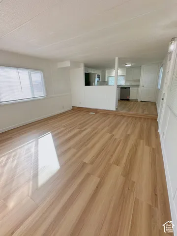 Open-concept interior featuring light-tone wood-finish flooring, white beadboard wall paneling, and a tiered floor elevation