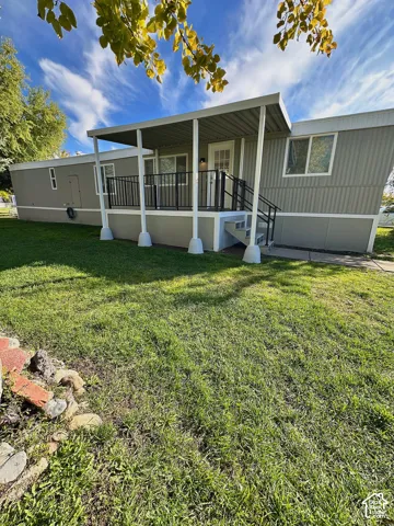 Exterior featuring a covered porch with metal roofing, metal railings, and a concrete pathway