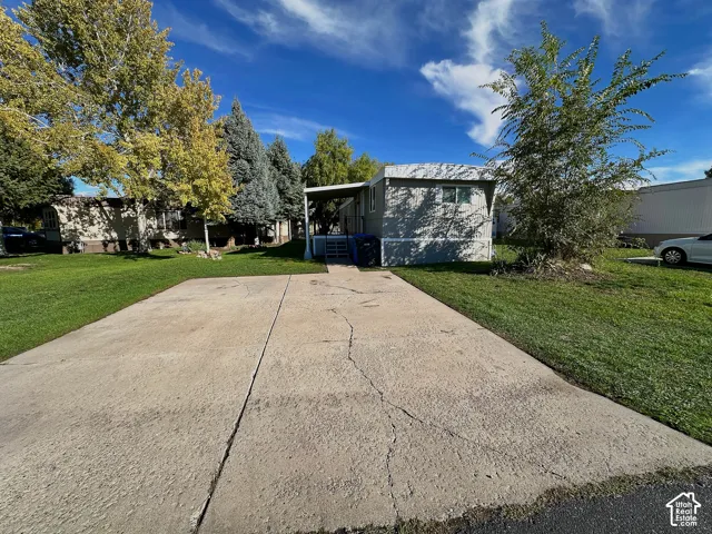 Exterior featuring light-toned metal siding, a concrete parking pad, and a covered entry porch