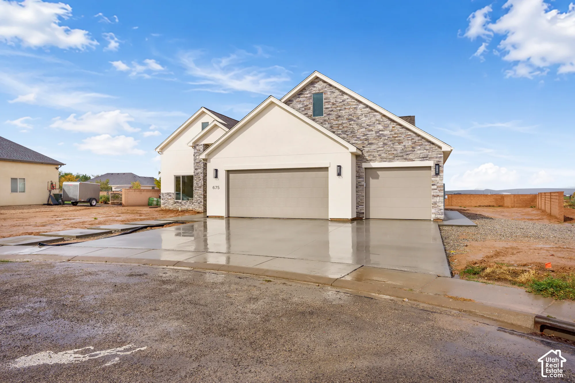 Contemporary exterior featuring a combination of stucco and masonry stone siding, an attached three-car garage, and a concrete driveway