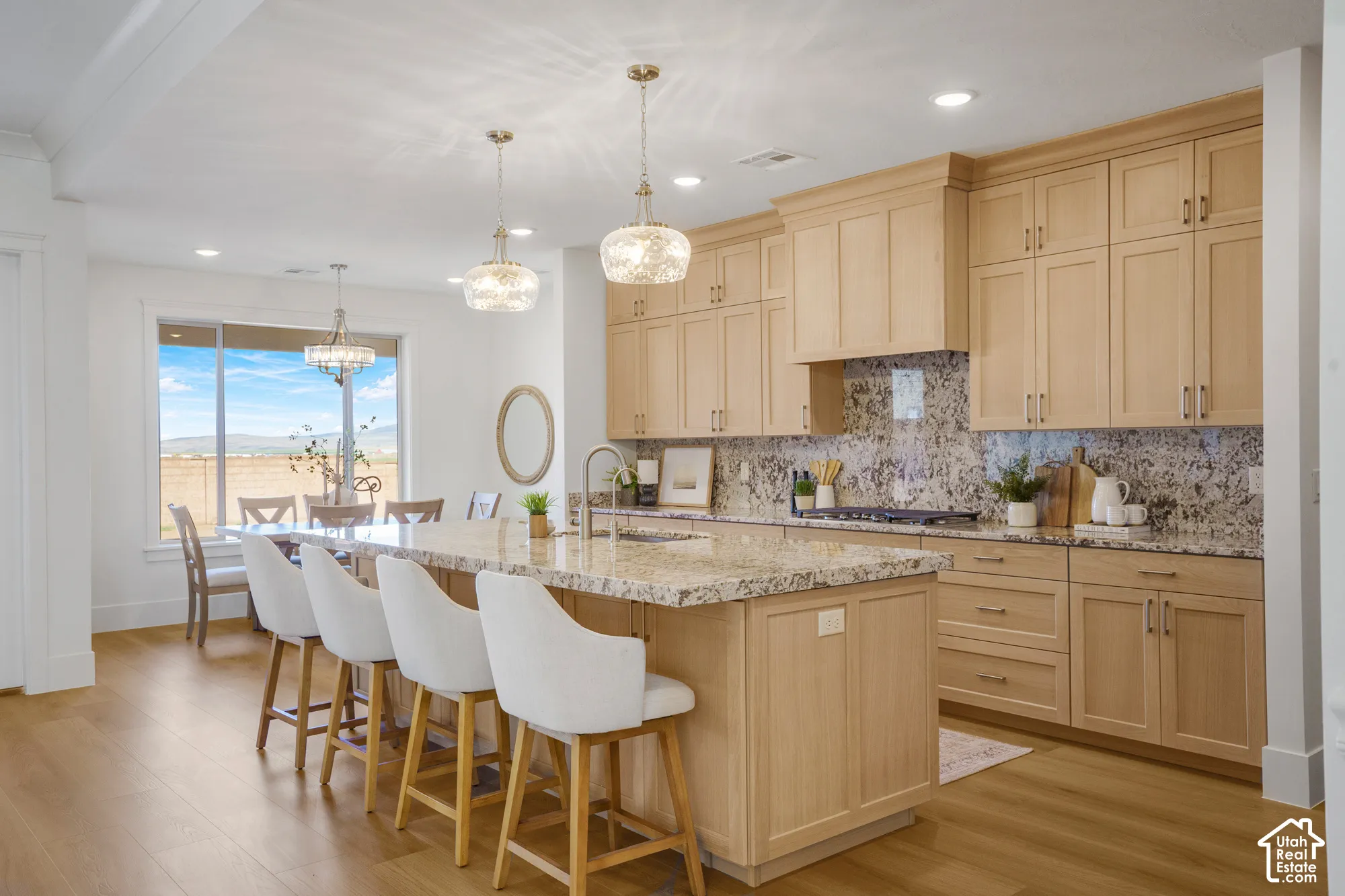 Kitchen featuring light-finish wood cabinetry, stone countertops, central island, wood-finish flooring, and pendant lighting