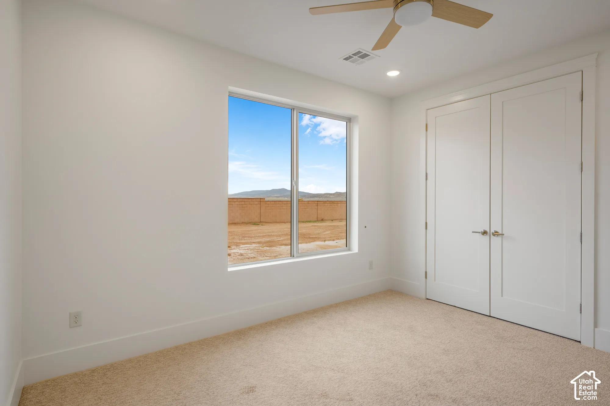 Neutral-toned carpeted flooring, double-door closet with brushed nickel hardware, recessed lighting, and a ceiling fan with light fixture