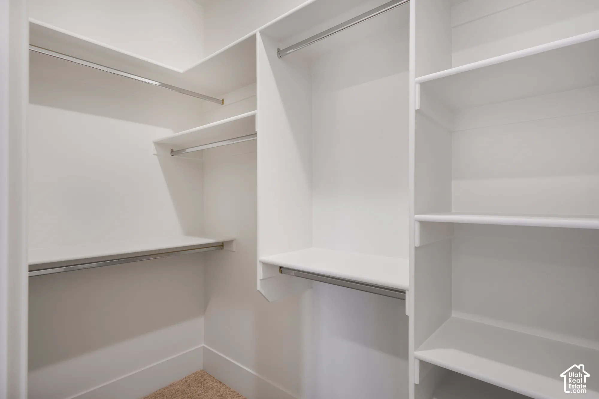 Walk-in closet featuring white custom shelving, tiered hanging rods, and integrated cabinetry