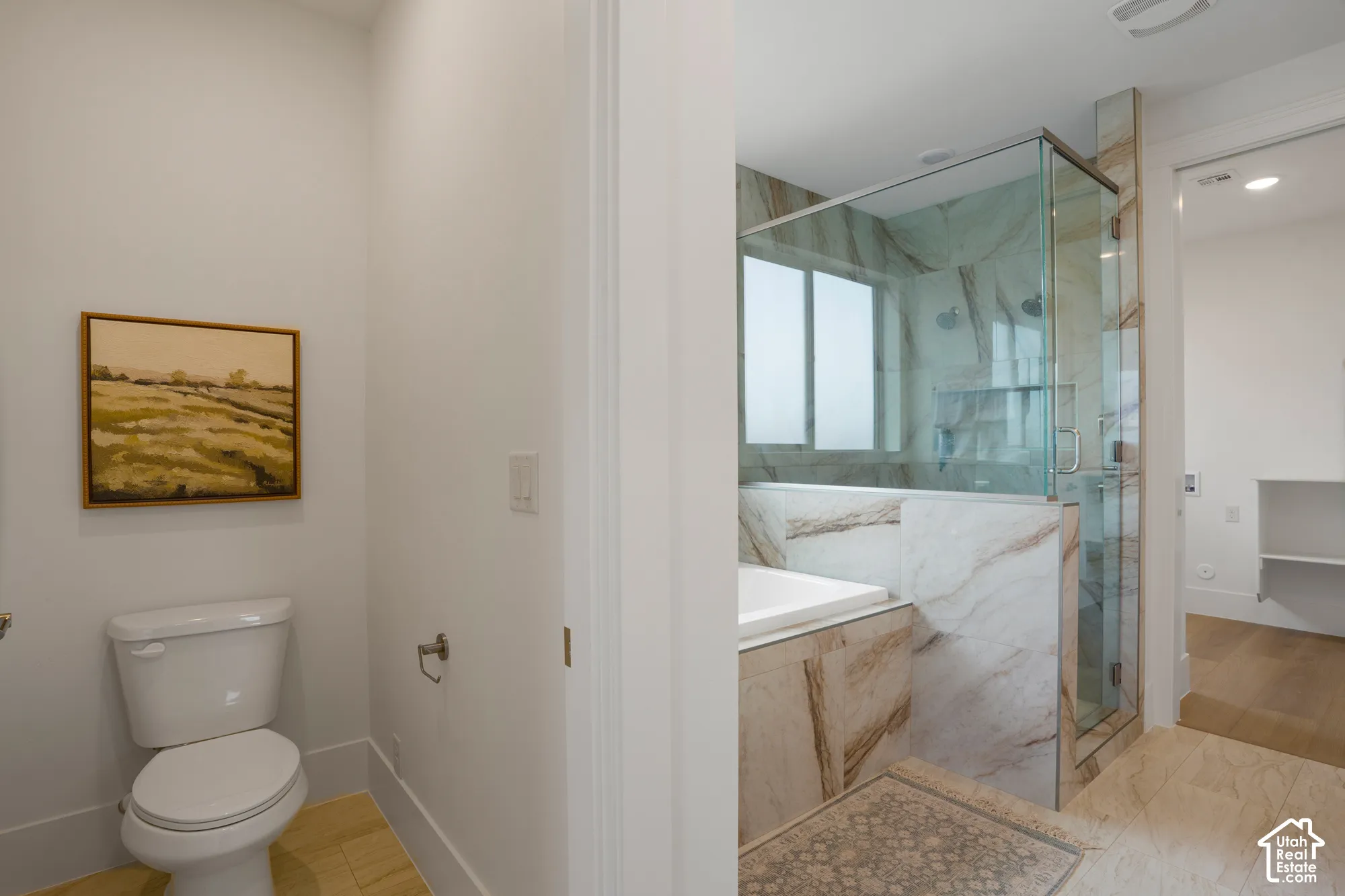 Bathroom featuring large-format tile flooring, a soaking tub, and a walk-in glass-enclosed shower with floor-to-ceiling tile surround