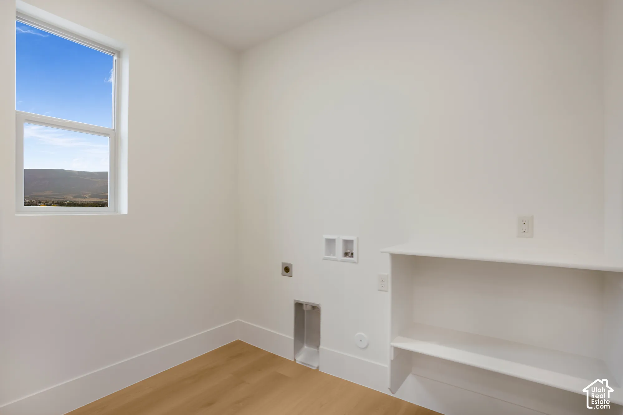 Room featuring wood-finish flooring, a single-hung window with mountain backdrop, and built-in shelving
