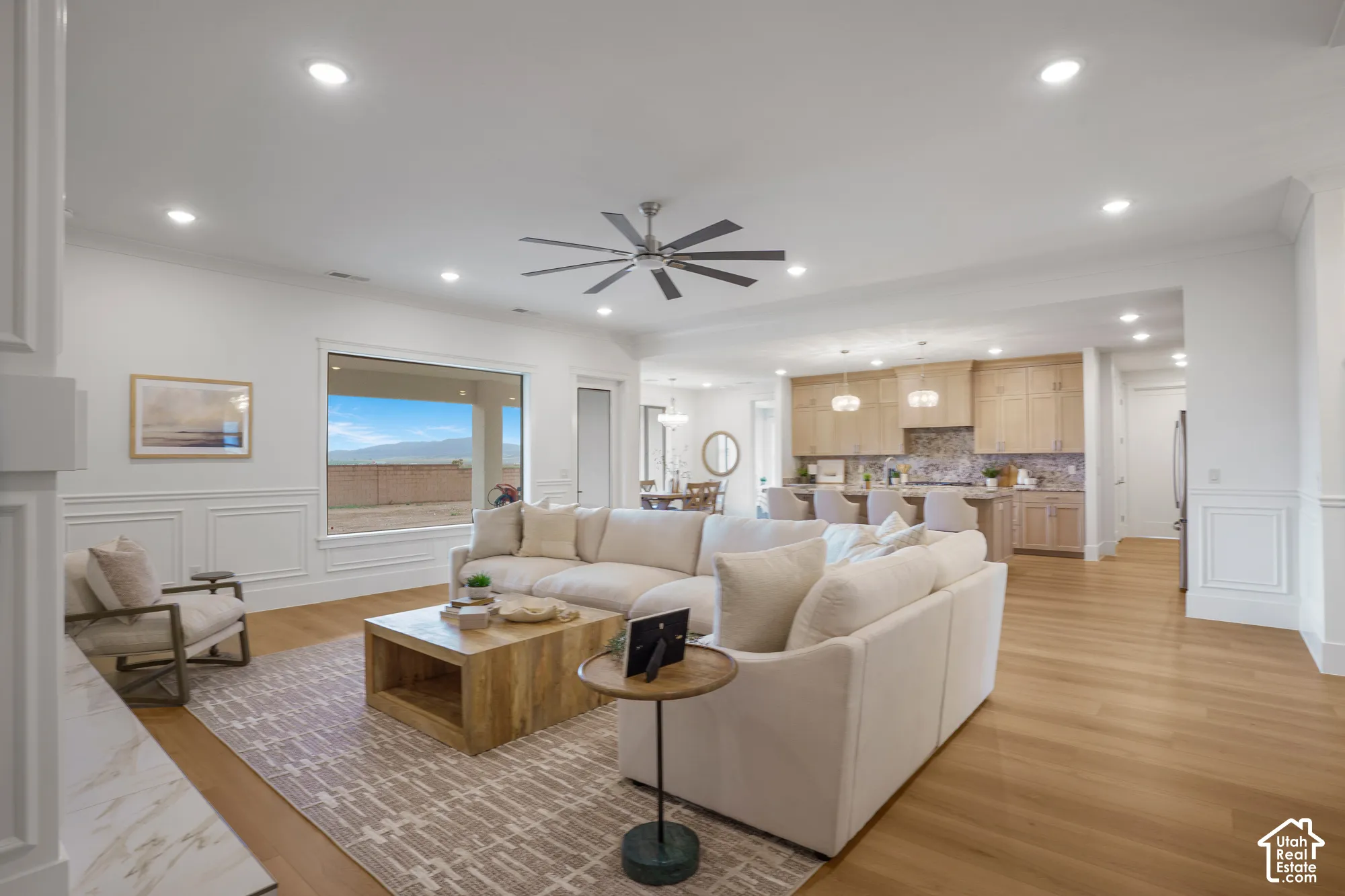 Open-concept interior featuring light wood-finish flooring, wainscoting, recessed lighting, and a multi-blade ceiling fan