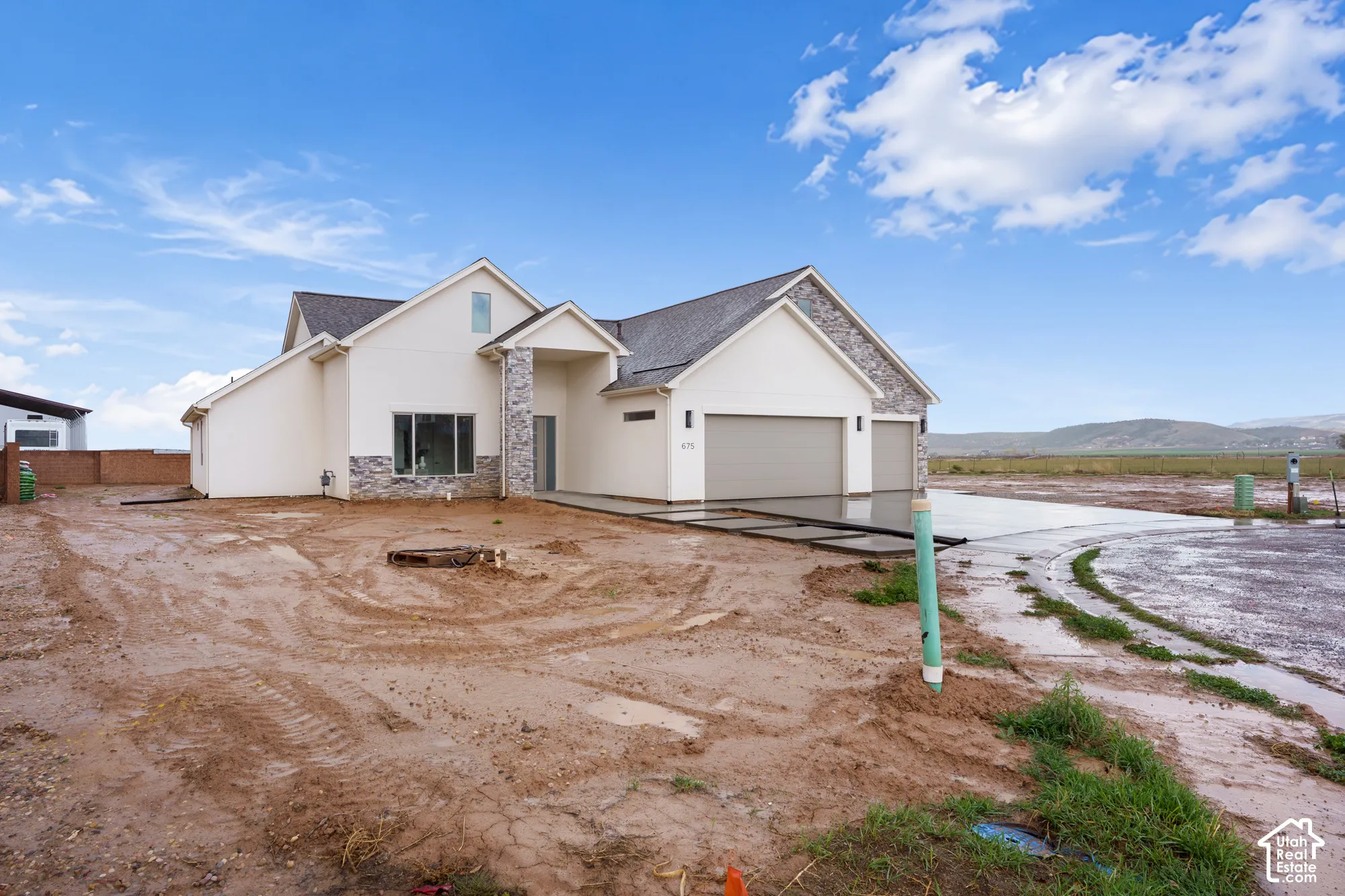 Contemporary exterior featuring stucco siding, stone veneer accents, multi-gabled roofline, and a three-car attached garage