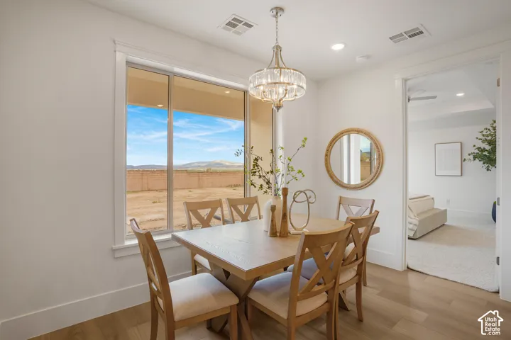 Dining space featuring wood-finish flooring, a multi-light crystal chandelier, and a large window with mountain terrain scenery