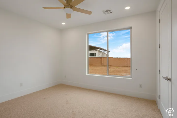 Neutral-toned wall-to-wall carpeting, ceiling fan with integrated lighting, recessed lighting, and large sliding window