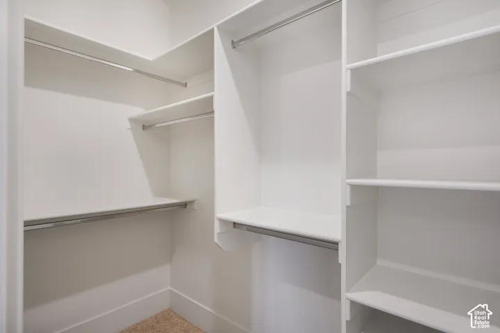 Walk-in closet featuring white custom shelving, tiered hanging rods, and integrated cabinetry