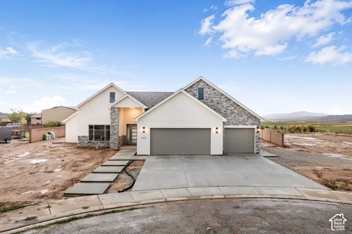 Exterior facade featuring multi-gabled rooflines, stone veneer accents, stucco siding, and a three-car garage