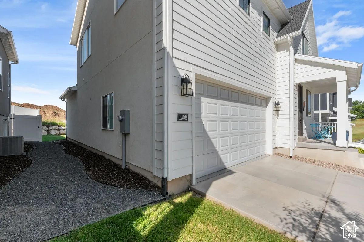 Exterior featuring horizontal lap siding, a concrete driveway, a multi-panel garage door, a covered porch entrance, and a gravel pathway along the side of the property