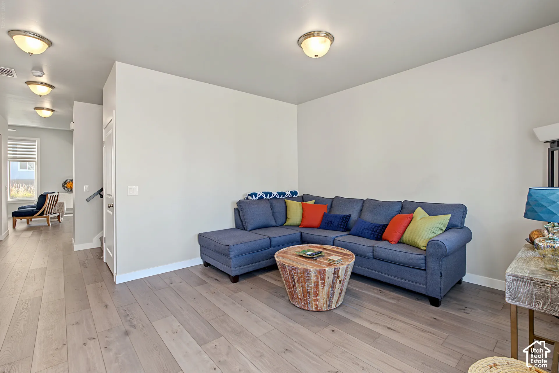 Neutral interior room featuring wood-finish flooring and multiple flush-mount ceiling light fixtures