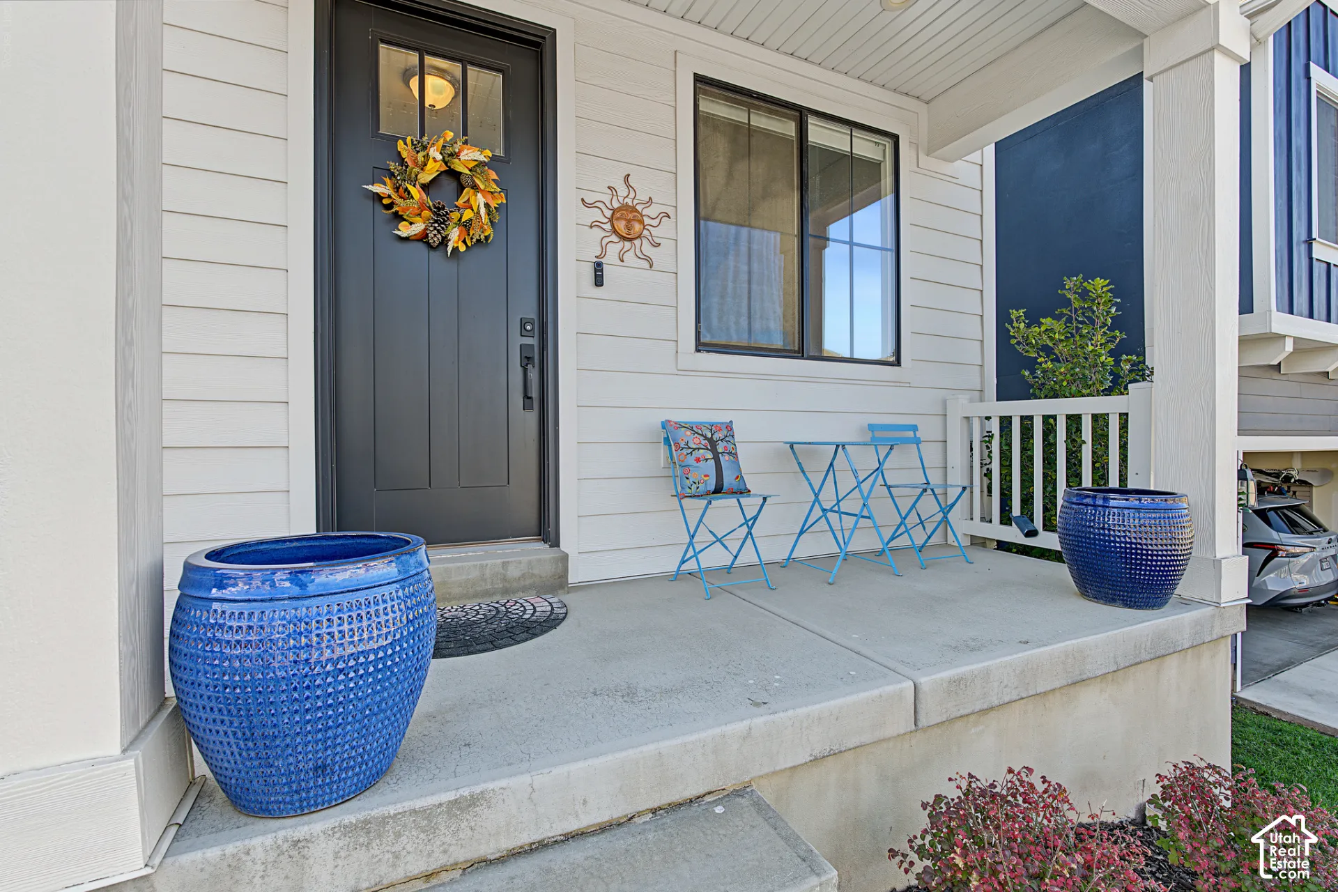 Covered front porch with concrete flooring, horizontal lap siding, and a dark-toned front door featuring an inset glass panel