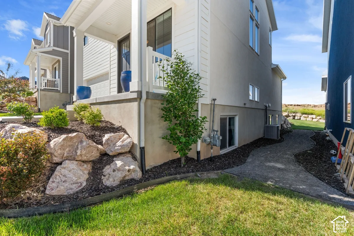 Exterior facade featuring horizontal lap siding, a covered front porch with white railing, concrete foundation, and decorative boulder landscaping