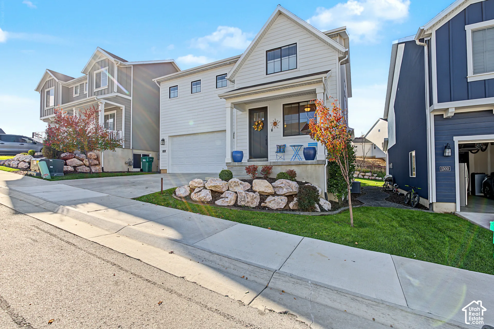Two-story exterior with horizontal siding, a covered front porch, an attached garage, and decorative stone landscaping