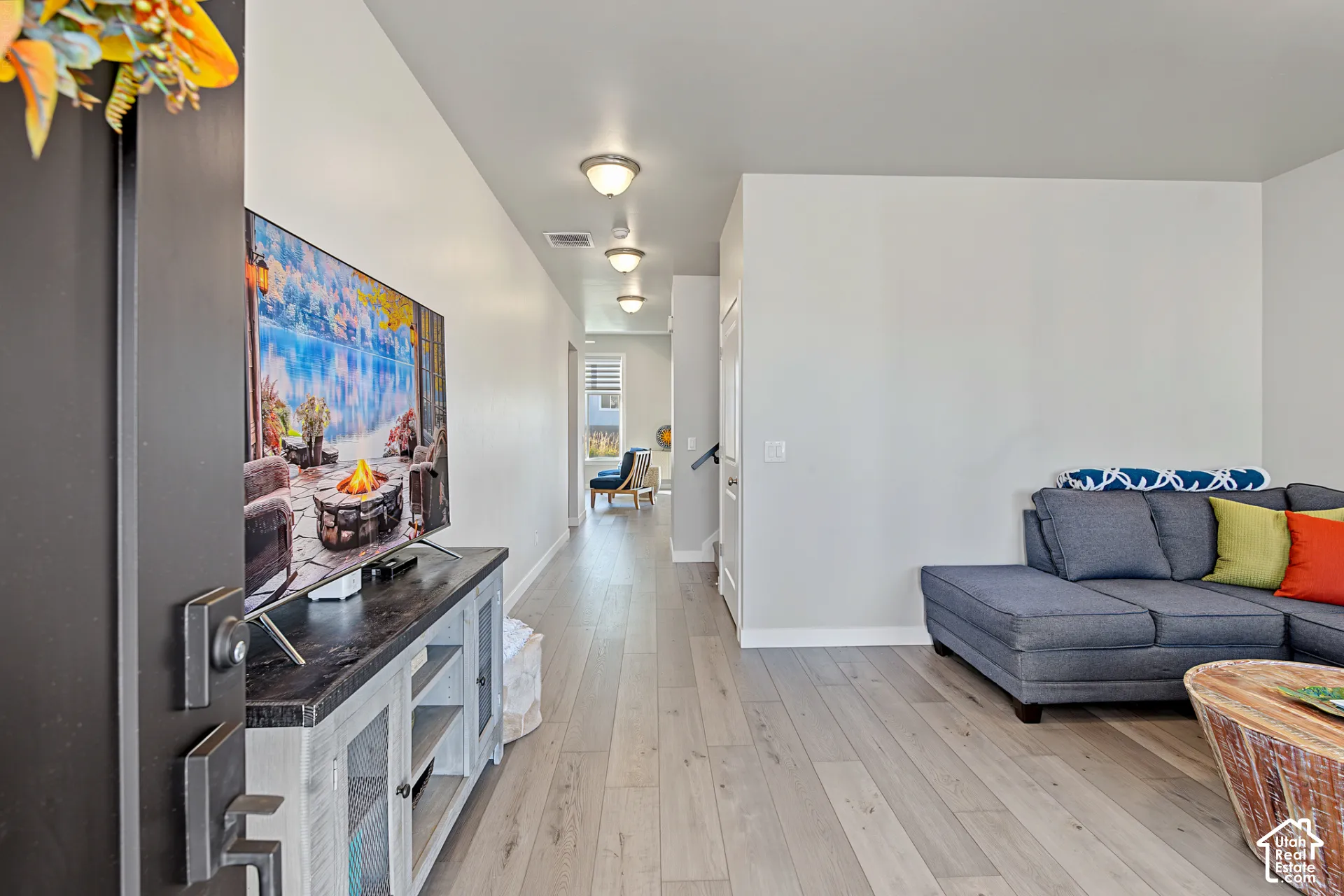Open floor plan featuring wood-finish flooring, neutral wall paint, and multiple flush-mount ceiling light fixtures