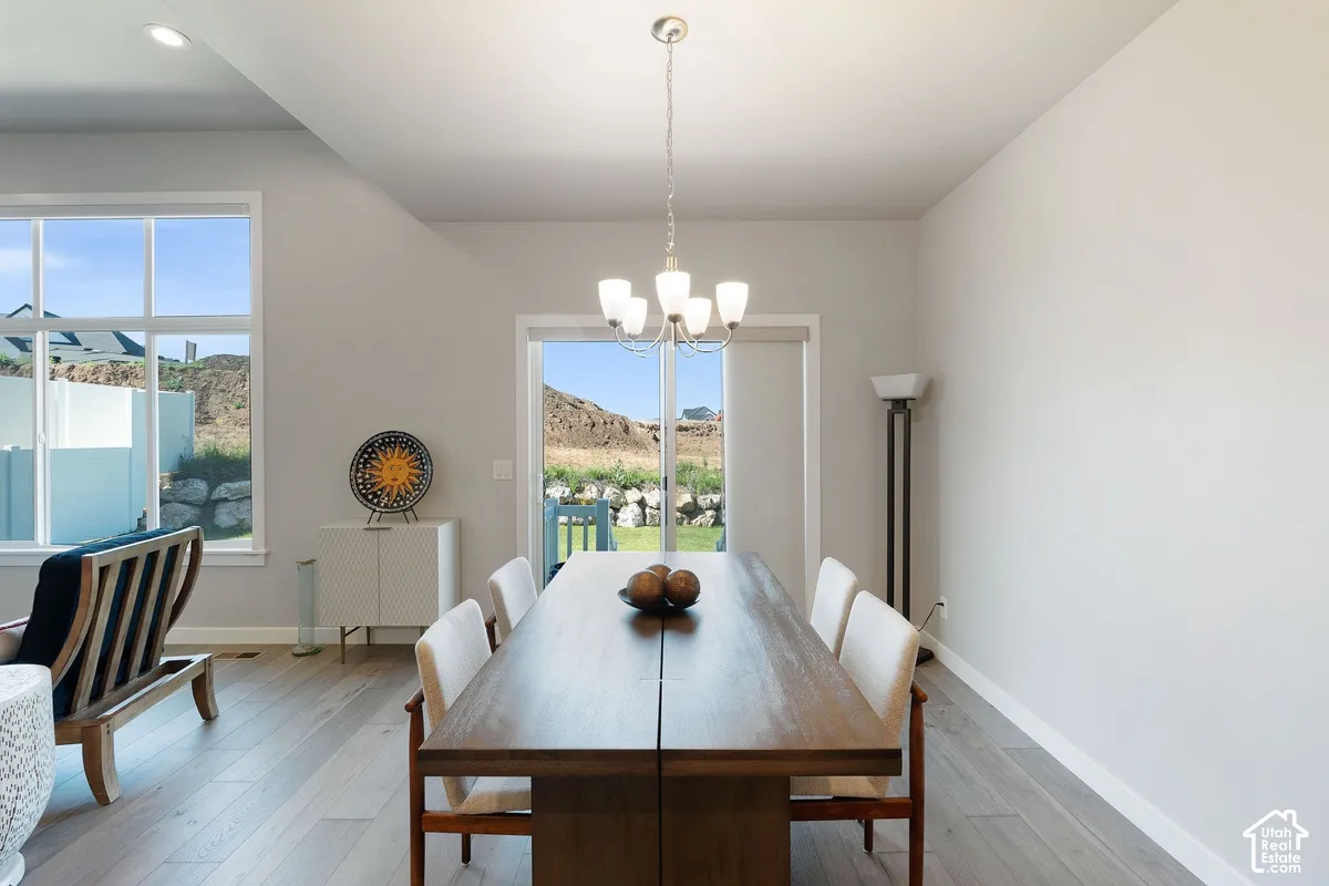 Dining area featuring wood-finish flooring, a multi-light chandelier, expansive windows, and a sliding glass door
