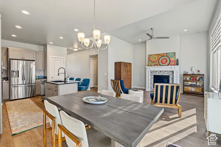 Open-concept kitchen and living area featuring recessed lighting, stainless steel appliances, wood-finish flooring, a kitchen island with stone surfacing, and a fireplace with a mosaic tile surround