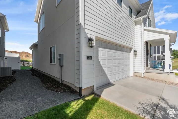 Exterior featuring horizontal lap siding, a concrete driveway, a multi-panel garage door, a covered porch entrance, and a gravel pathway along the side of the property