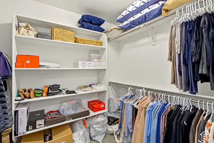 Walk-in closet featuring white built-in shelving and dual-level metal garment rods