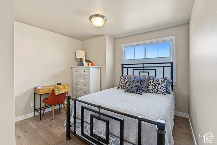 Room featuring wood-finish flooring, neutral wall paint, and a sliding window with clean white trim