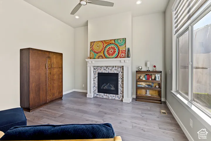 Fireplace featuring a white mantel and multi-toned tile surround, wood-finish flooring, high ceilings, and expansive windows