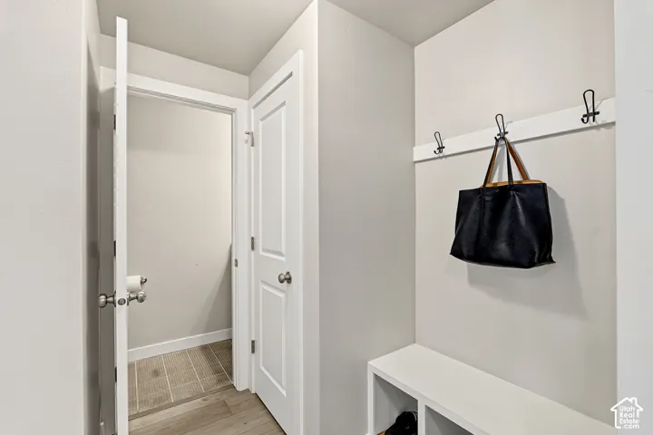Built-in storage bench with lower shelving, mounted coat hooks, two-panel interior doors, and neutral wall tones