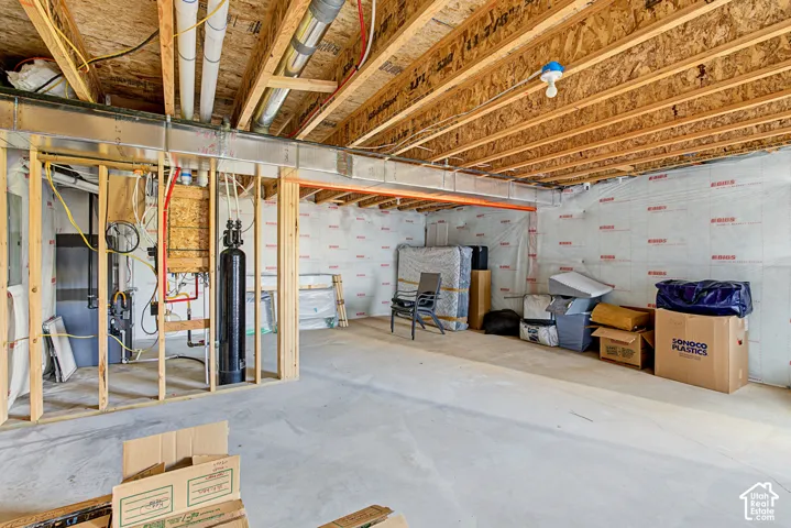 Unfinished basement space featuring exposed wood joist ceilings, concrete flooring, insulated foundation walls, and an installed water filtration system