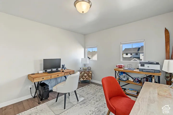 Room featuring wood-finish flooring, neutral wall paint, dual windows, and a flush-mount ceiling light fixture