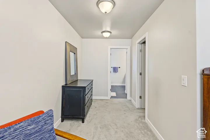 Interior hallway featuring neutral wall paint, wall-to-wall carpeting, and dual flush-mount ceiling light fixtures