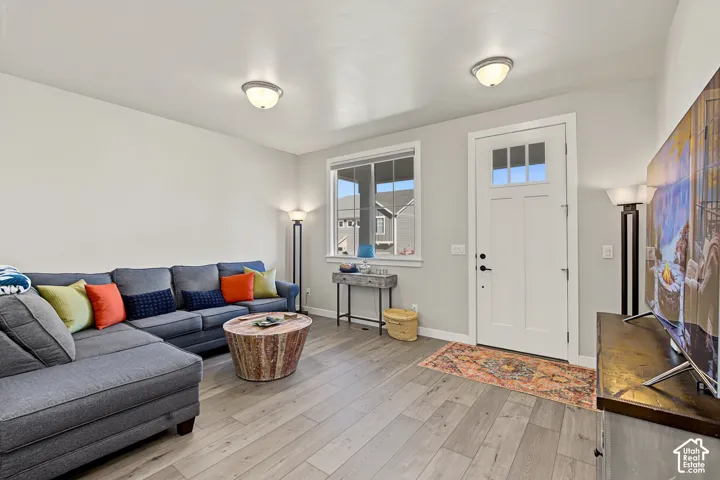 Living area featuring wood-finish flooring, neutral wall paint, and a single-panel exterior door with a multi-pane glass insert
