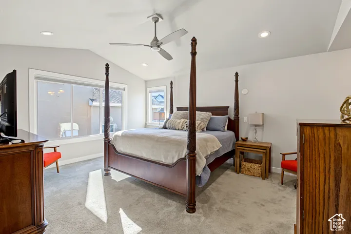 Vaulted ceiling featuring a ceiling fan, recessed lighting, and large windows with neutral wall finishes and carpeting