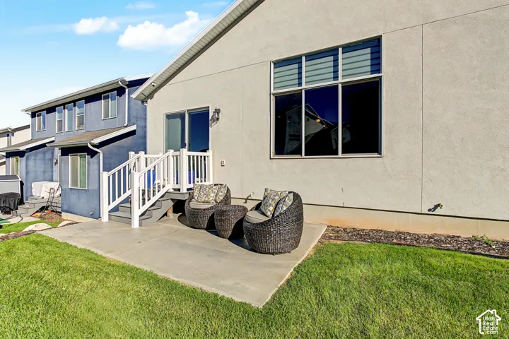 Stucco exterior featuring a concrete patio, elevated deck with white railing, and multi-pane windows