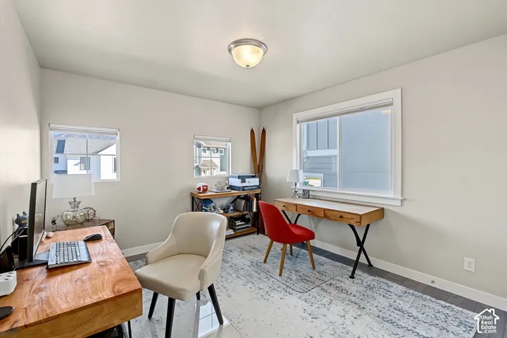 Room with neutral walls, wood-finish flooring, three windows with white casings, and a flush-mount ceiling light fixture