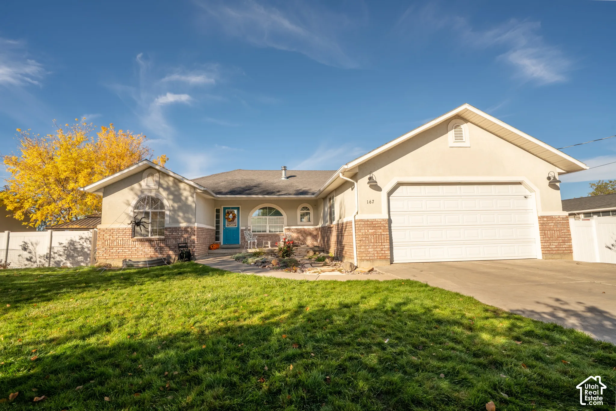 Single-story residence featuring a mixed stucco and masonry exterior, an attached two-car garage, arched windows, and a paved driveway