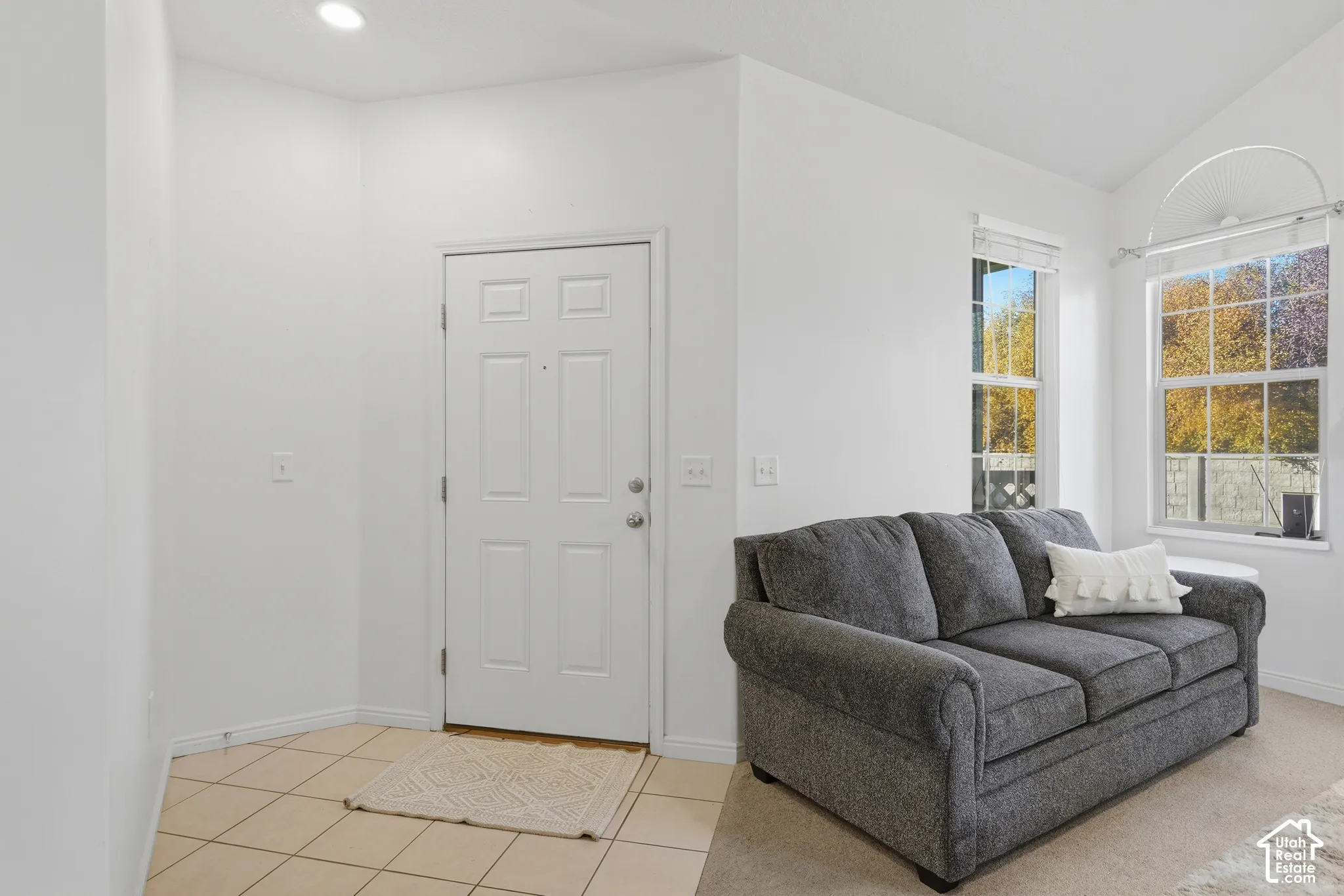 Vaulted ceilings, neutral tile flooring in the entryway, wall-to-wall carpeting, and double-pane windows
