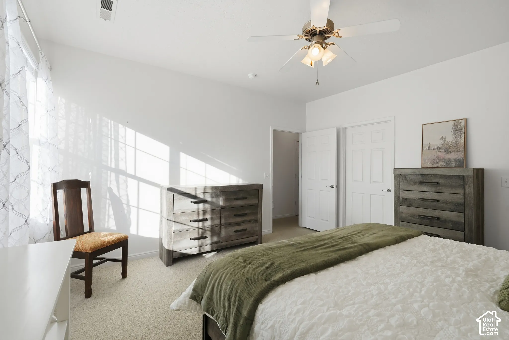 Neutral wall-to-wall carpeting, ceiling fan with integrated lighting, multi-pane window, and two-panel interior doors